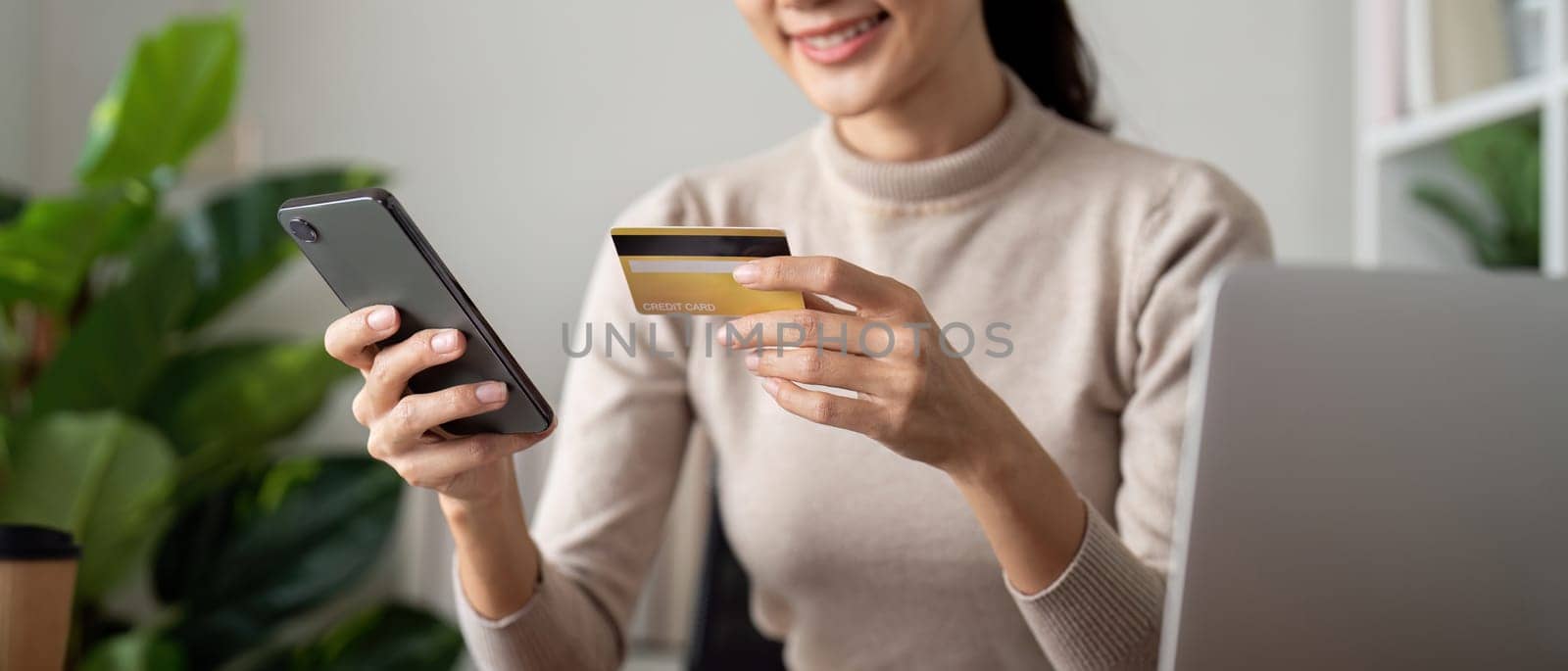 Online payment, Woman hands holding a credit card and using smartphone for online shopping at home by nateemee