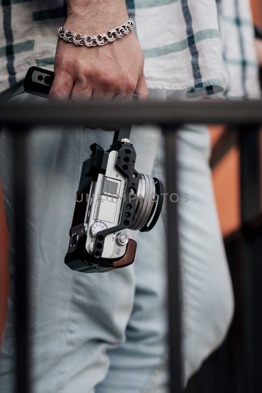 a male videographer holds a compact mirrorless camera in his hands