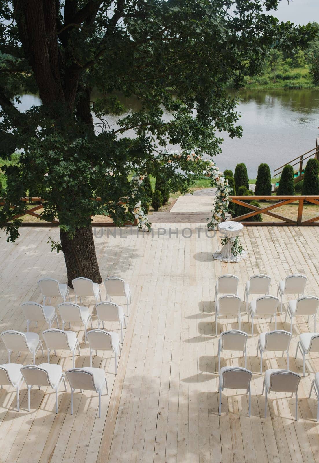 Wedding decor. Wooden chairs in the backyard banquet area. Arch for wedding ceremony a is decorated with flowers