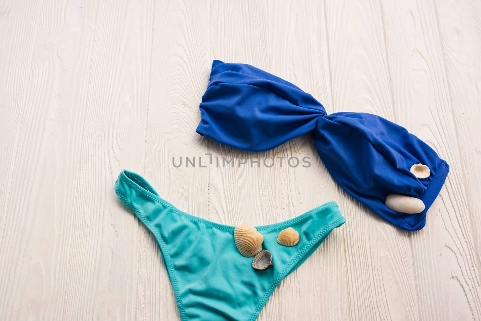 Women split multicolor blue swimsuit bikini. Summer background mockup template. pattern top view above swimwear white wooden background. accessories clothes beach. Women summer design vacation