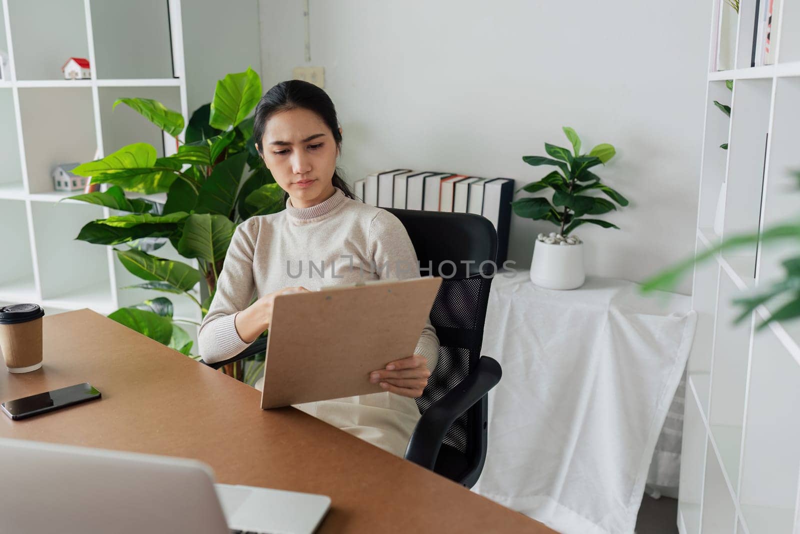 Businesswoman working with paperwork at modern eco-friendly office surrounded by tree.