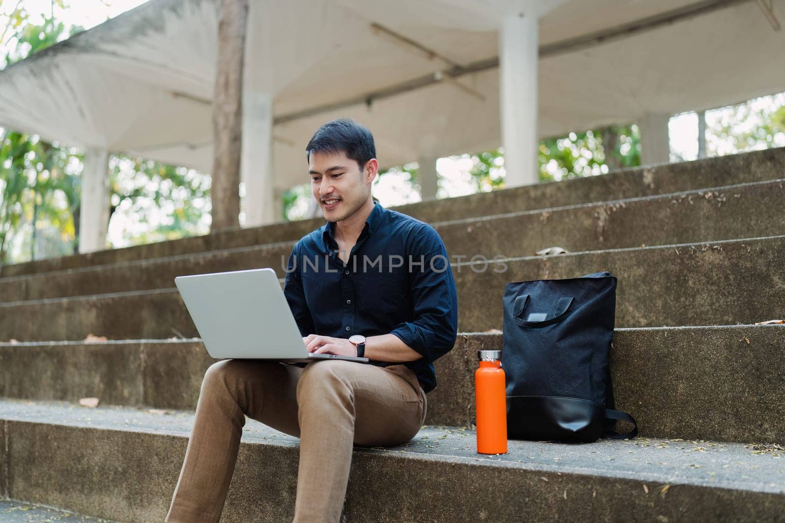 business man sitting on bench and working remotely on project with laptop.