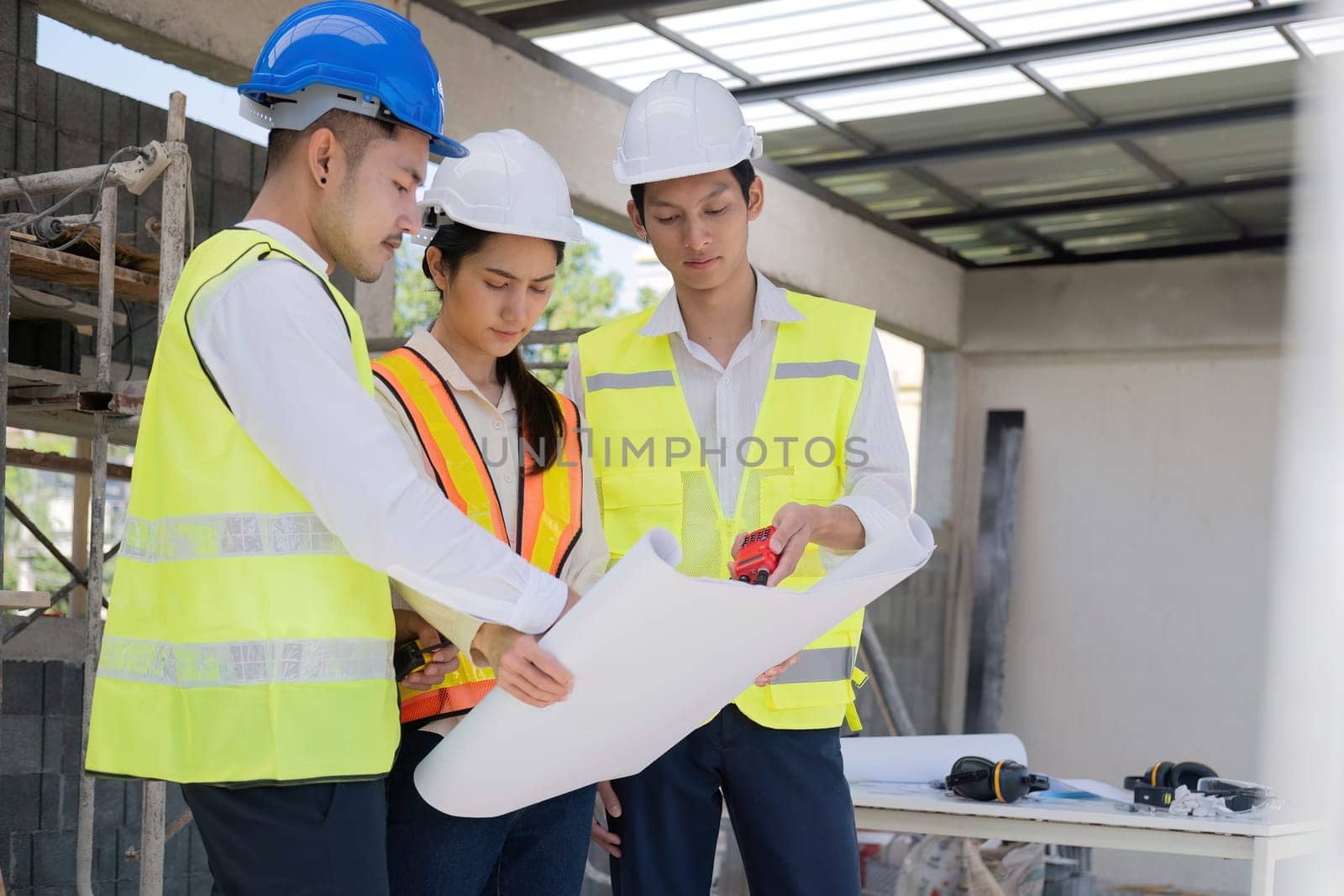 Civil engineer teams meeting working together wear worker helmets hardhat on construction site in modern city. Foreman industry project manager engineer teamwork. Asian industry professional team.