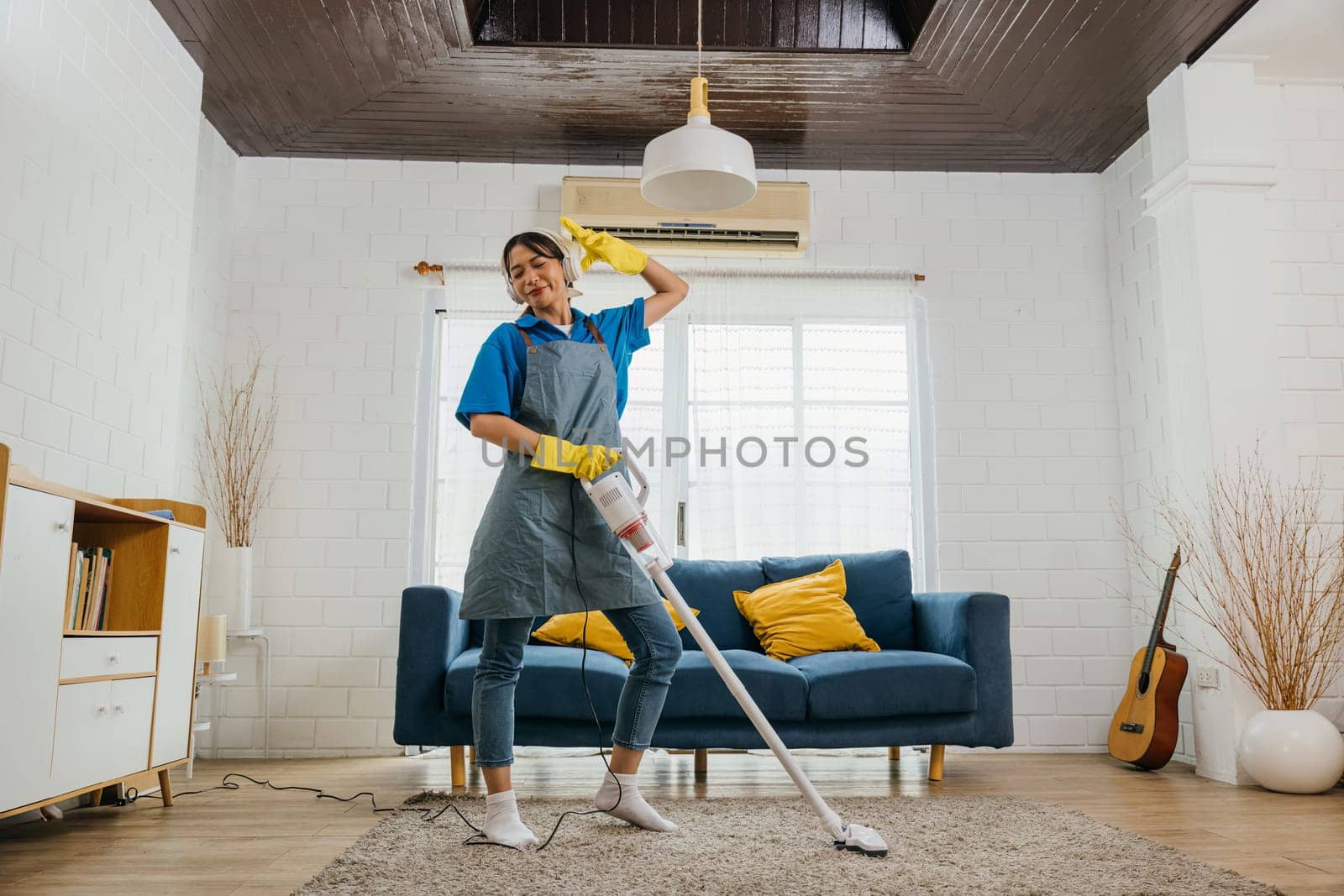 Asian housewife's fun cleaning, singing dancing with mop microphone. Joyful occupation filled with music laughter. Modern housework enjoyment. Give me a rhythm, maid dancing having fun