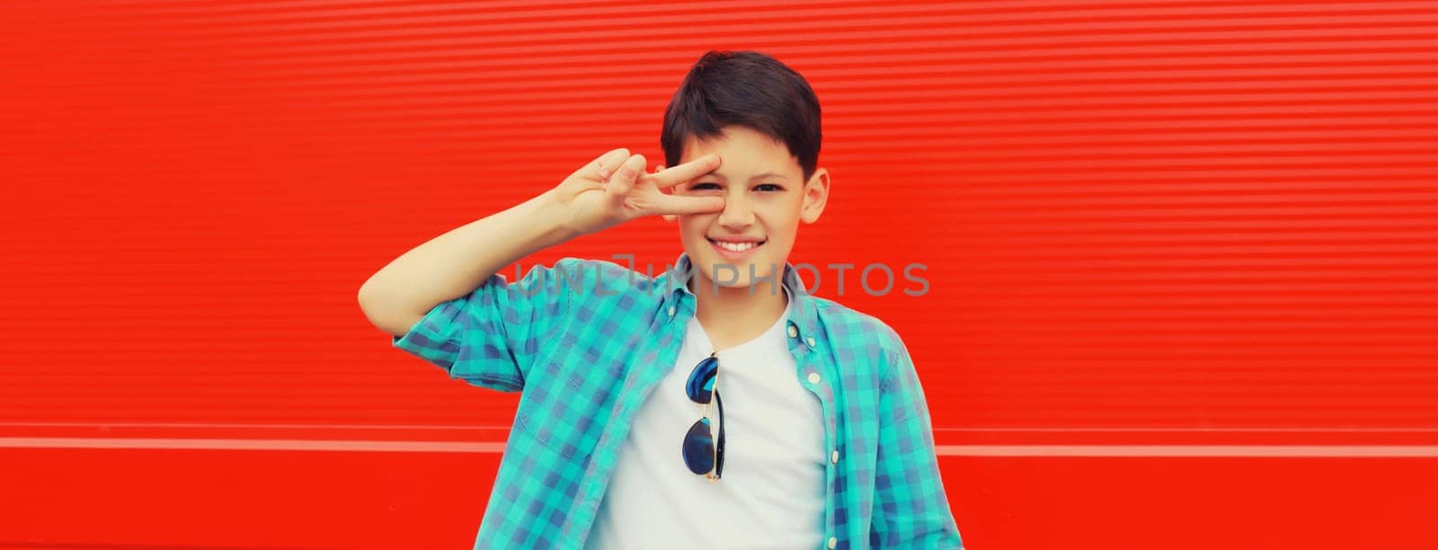 Portrait of happy smiling teenager boy in casual wear on red background