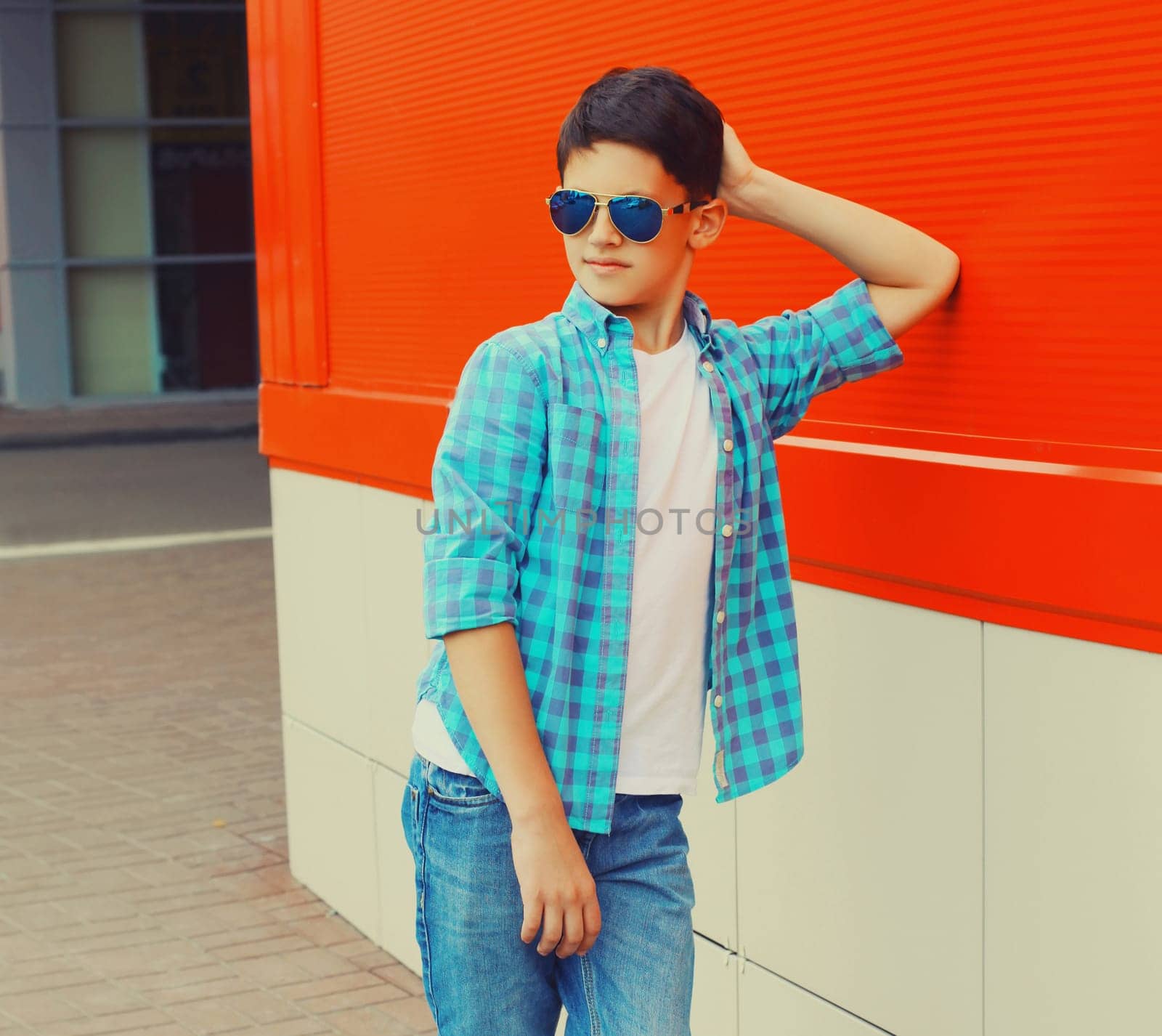 Teenager boy posing wearing sunglasses and shirt on the city street