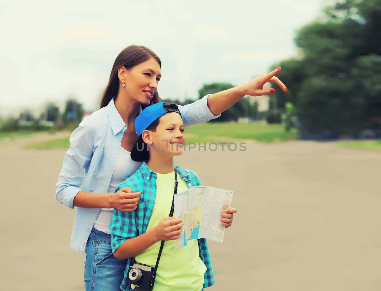 Happy mother with child son tourists sightseeing city with paper map together