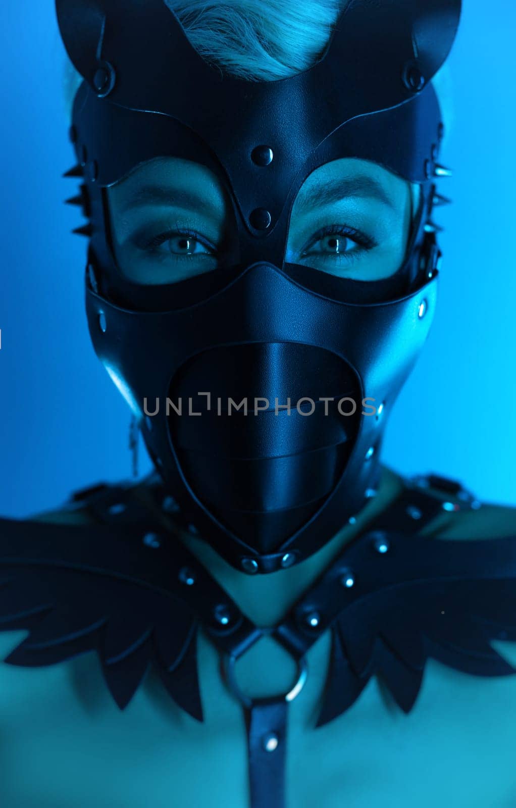 portrait of a hot sexy girl in a leather cat mask and muzzled in bdsm handcuffs on neon blue light by Rotozey
