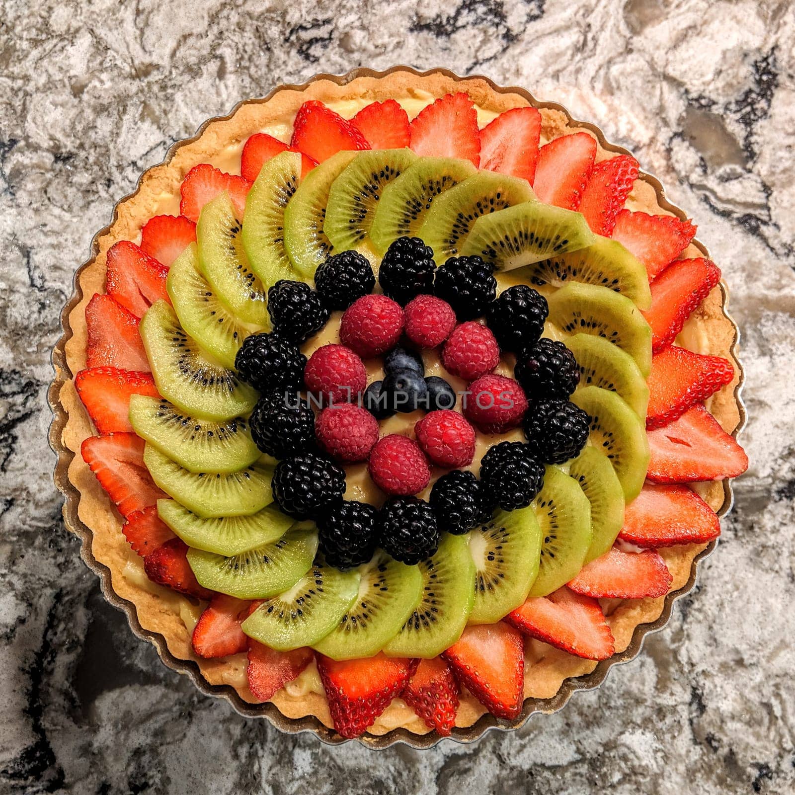 Top view of a vibrant, gourmet fruit tart on a marble surface, showcasing culinary art and healthy eating