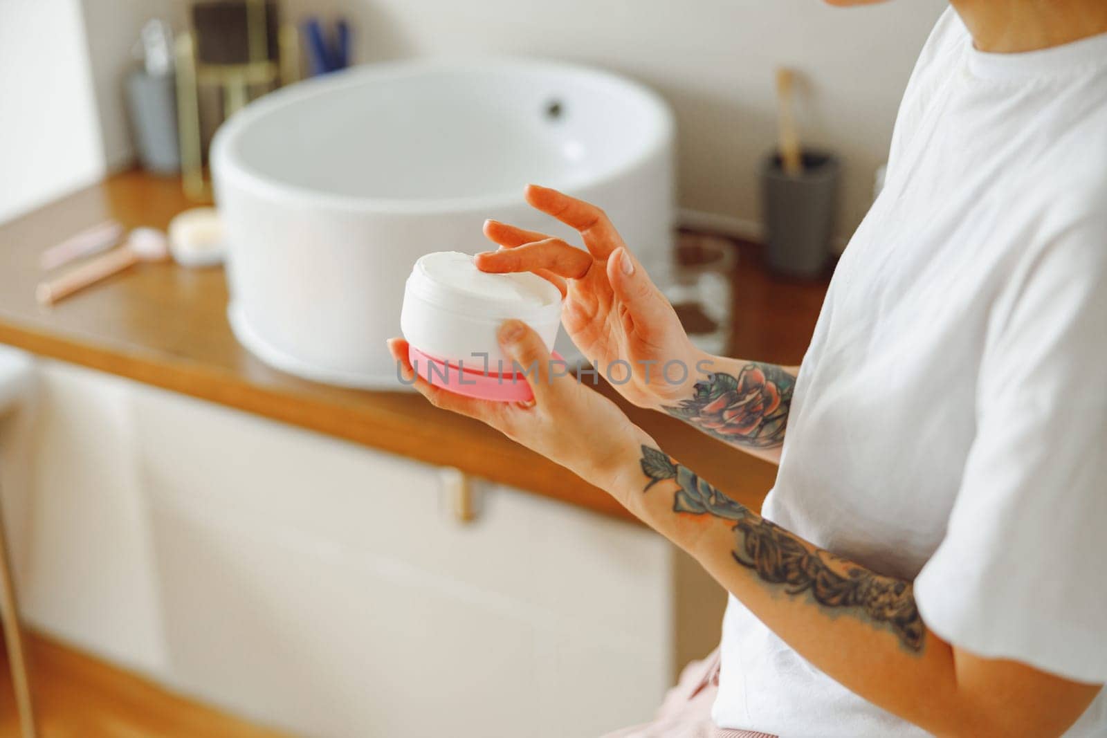 Close up of woman opening jar with face cream while standing in bathroom. High quality photo by Yaroslav_astakhov