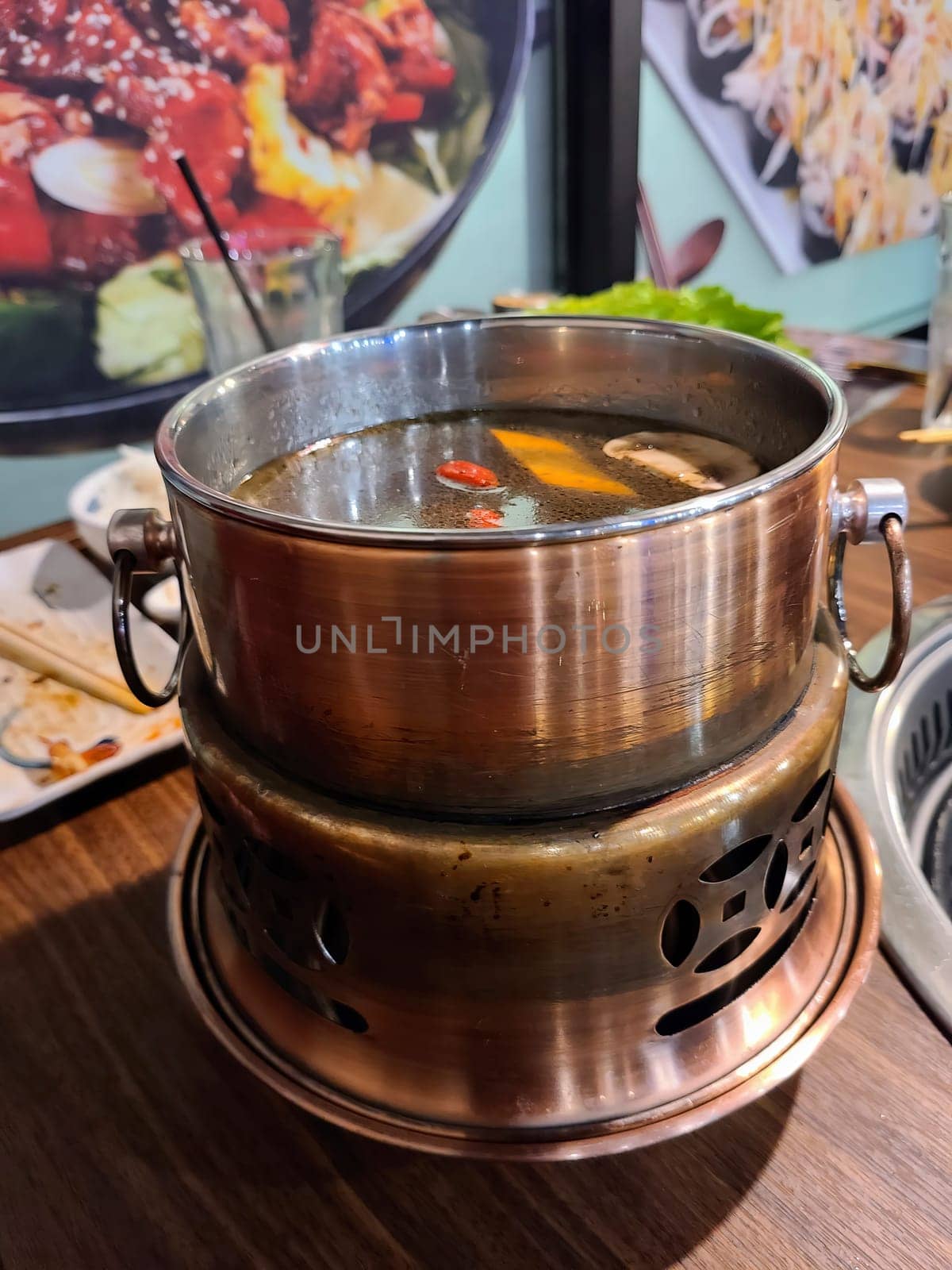 Steaming hot pot with mushrooms and goji berries in a cozy restaurant setting, showcasing communal dining in Fort Wayne, Indiana.
