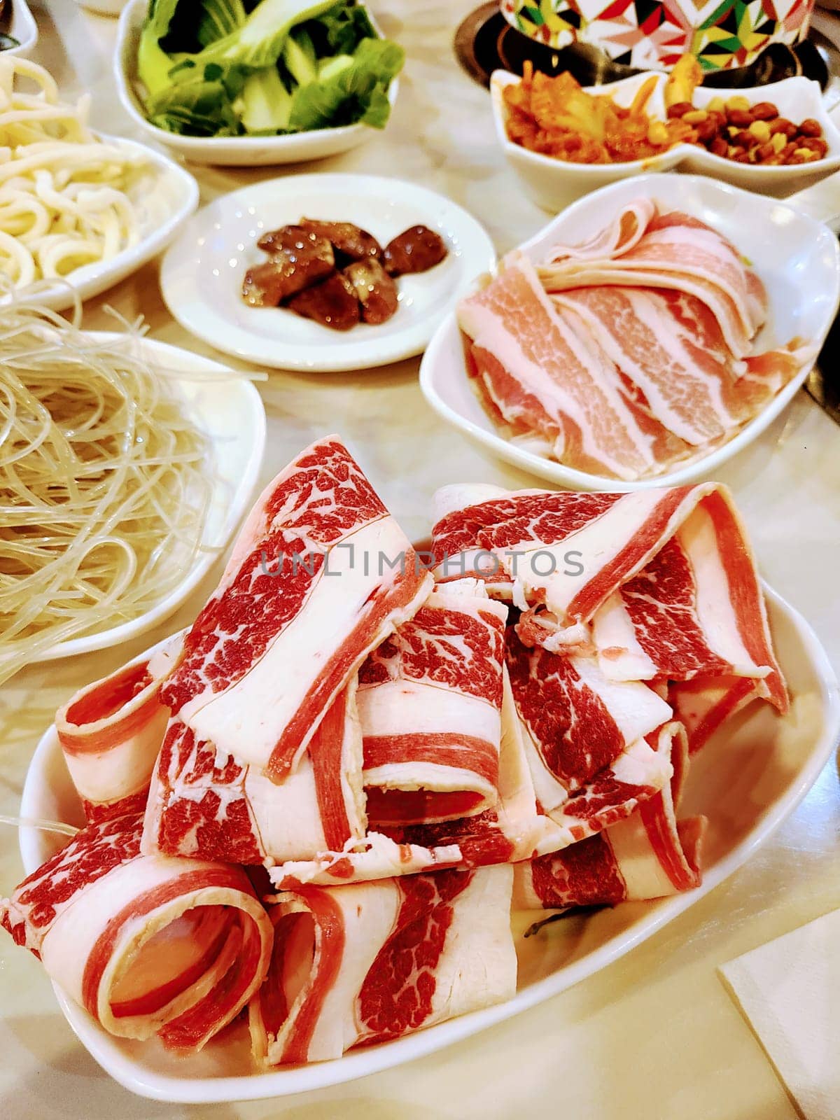 2022, Gourmet hot pot dining experience with marbled beef slices and fresh vegetables at a restaurant in Bloomington, Indiana