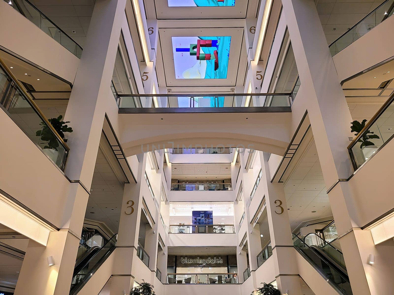 Multi-level modern shopping mall in Chicago, 2023, featuring a sleek glass design, digital advertising, and prominent escalators