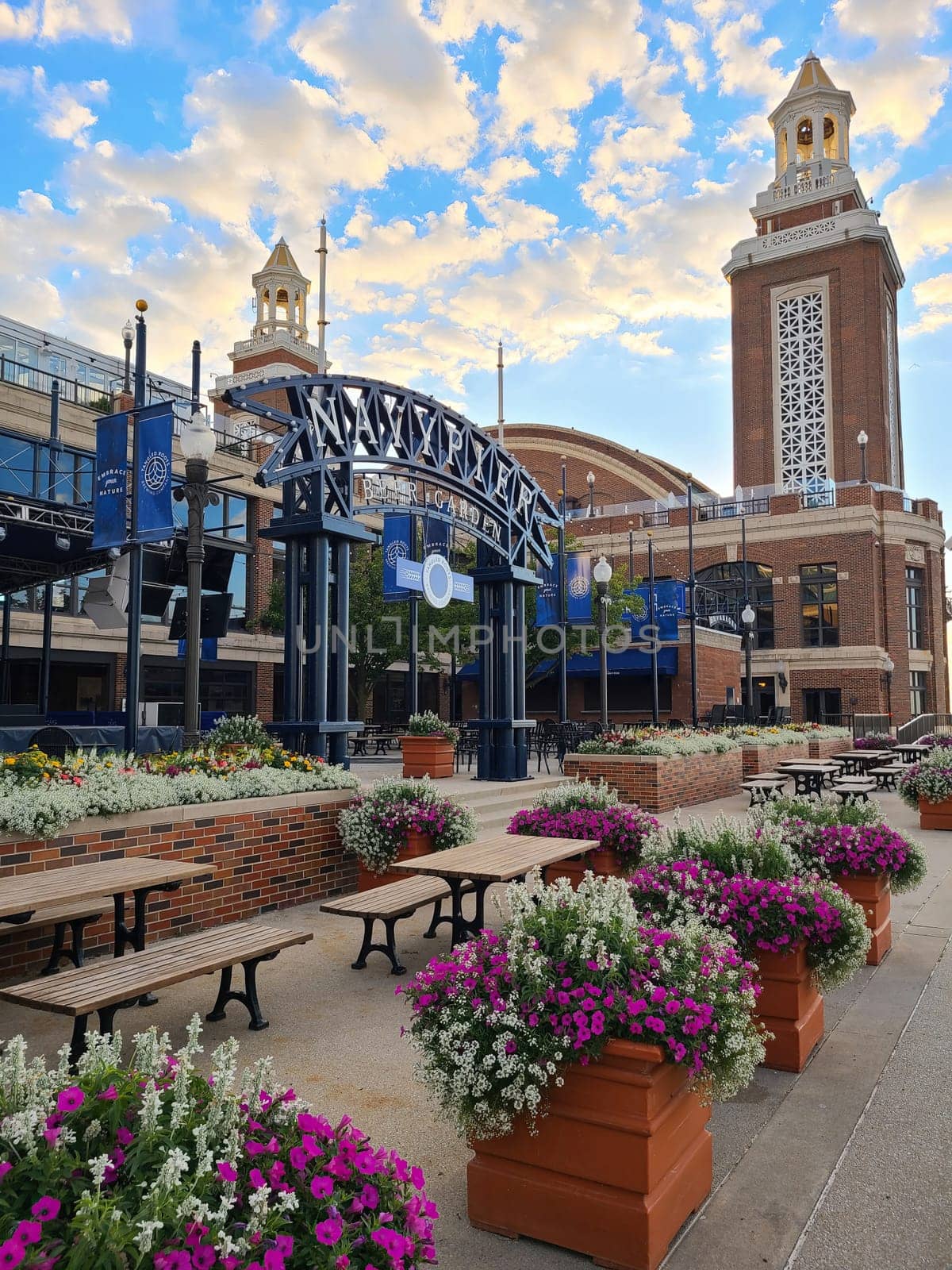 Colorful flower-filled planters at a leisurely outdoor dining area, with the historic architecture of Navy Pier, Chicago in the background on a clear day in 2022