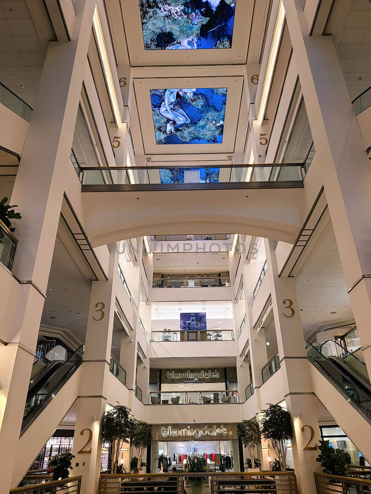 Modern multi-level shopping center interior in Chicago, 2023, featuring Bloomingdale's logo, large digital ceiling screens and sleek architectural design.