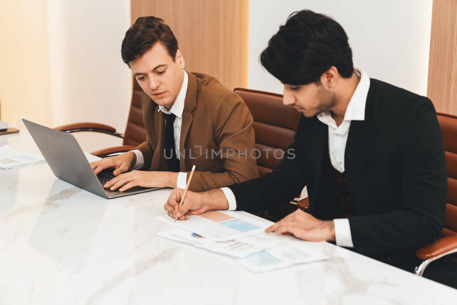 Businesspeople discussion about financial statistic. Manager using laptop analysis data while writing, planing market strategy on document at modern office. Business team working together. Ornamented.