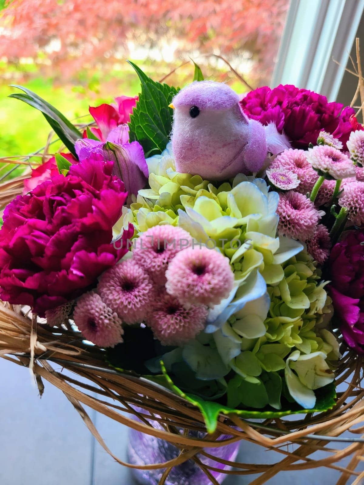 Vibrant spring arrangement in wicker basket with plush bird toy, Fort Wayne, Indiana 2023