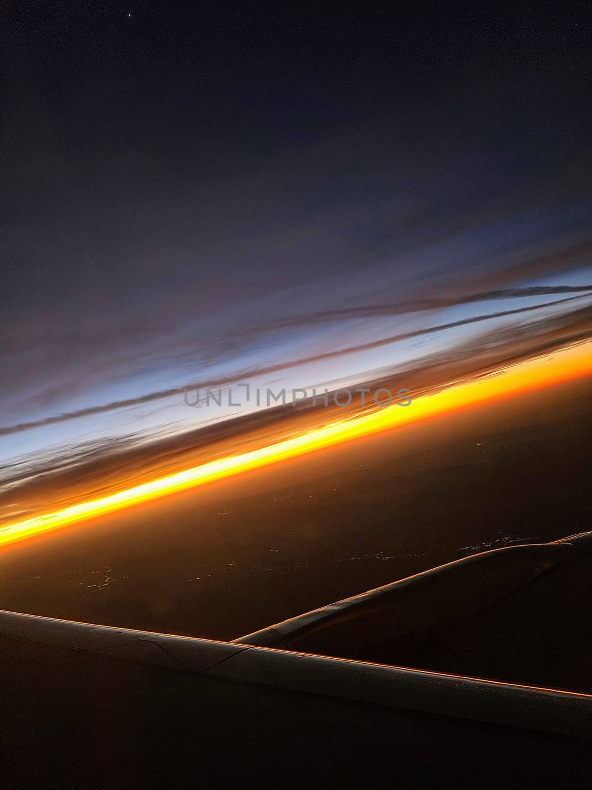 Airplane wing over the Bahamas at sunset, showcasing a vibrant horizon and serene clouds.