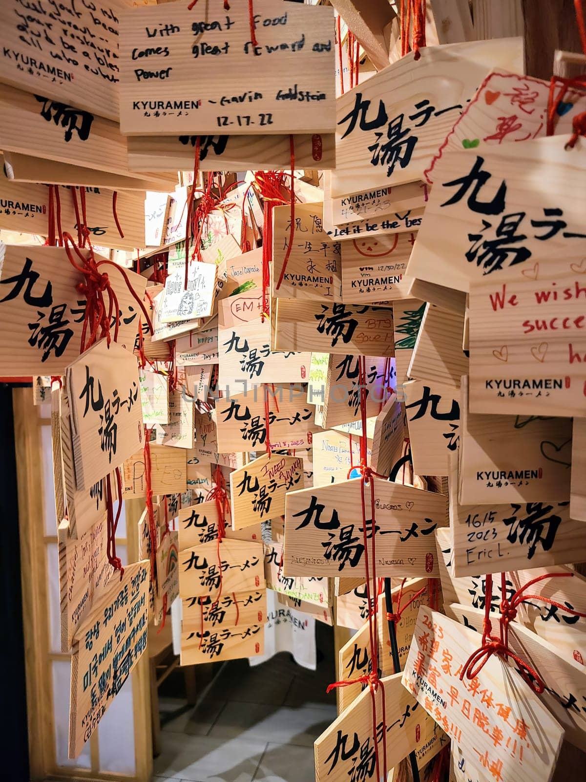 Dense collection of Ema, traditional Japanese wooden wishing plaques, hanging in a Chicago restaurant, Illinois, 2023, symbolizing hope, culture and community.