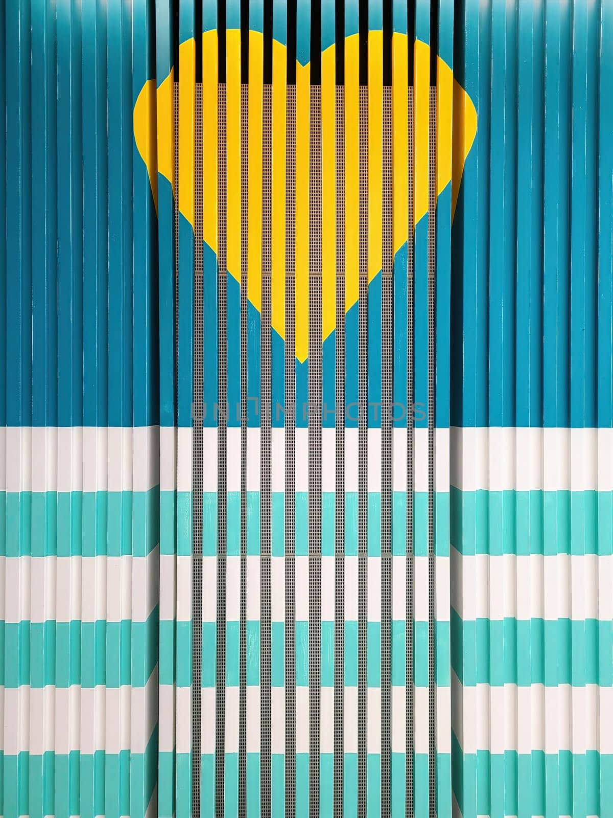 2023 abstract geometric design featuring a vibrant yellow heart centered on turquoise and blue stripes, symbolizing love within a structured environment, photographed in San Francisco, California.