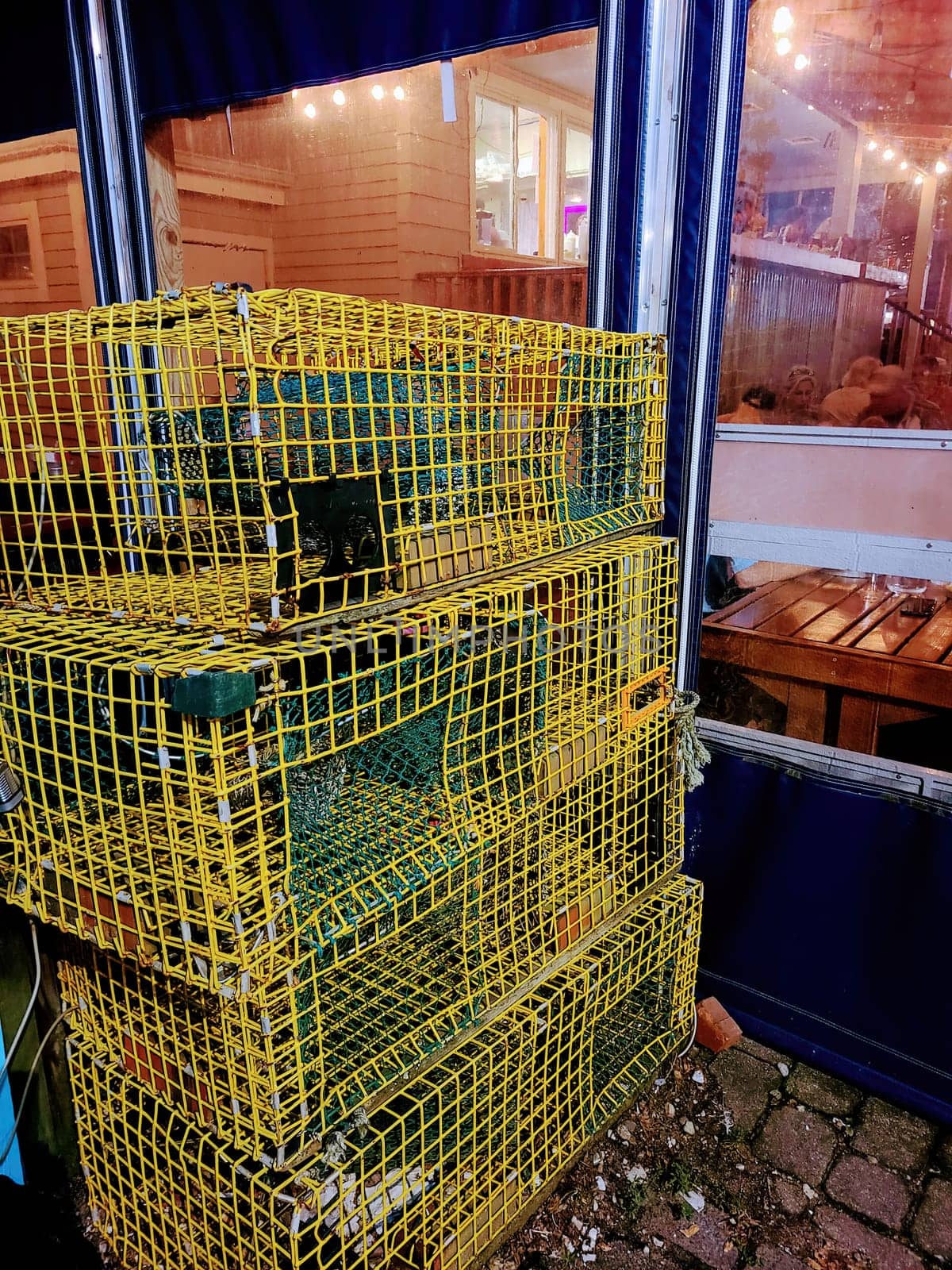 Colorful lobster traps leaning against a seafood restaurant in rustic Old Orchard Beach, Maine, under evening glow, 2022