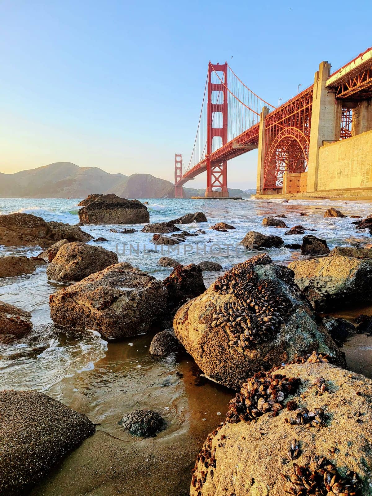 Golden Gate Bridge at Sunset, California 2022 - Iconic Structure Seen from Rocky Shoreline with Mussels