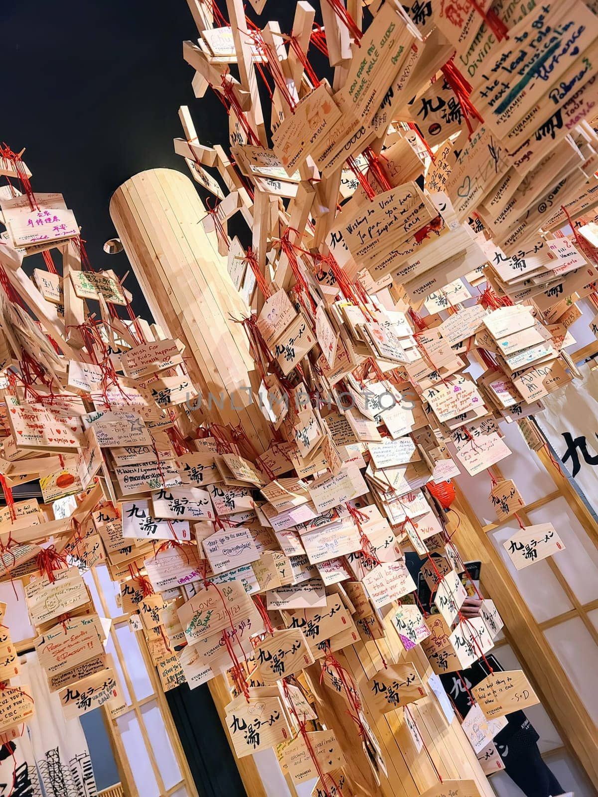 Diverse wishes on traditional Japanese ema plaques at a 2023 Shinto shrine exhibit in a Chicago restaurant