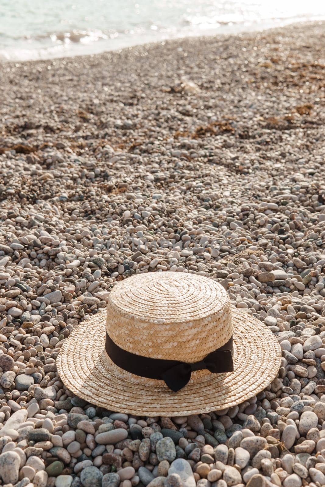 A straw hat on the beach. Pebbles on the seashore, close-up. The natural background.