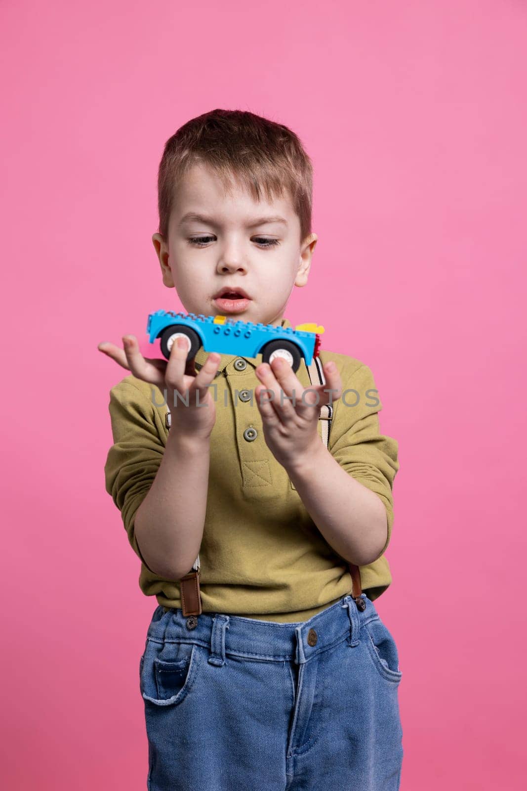 Small young boy playing with a blue vehicle toy in studio by DCStudio