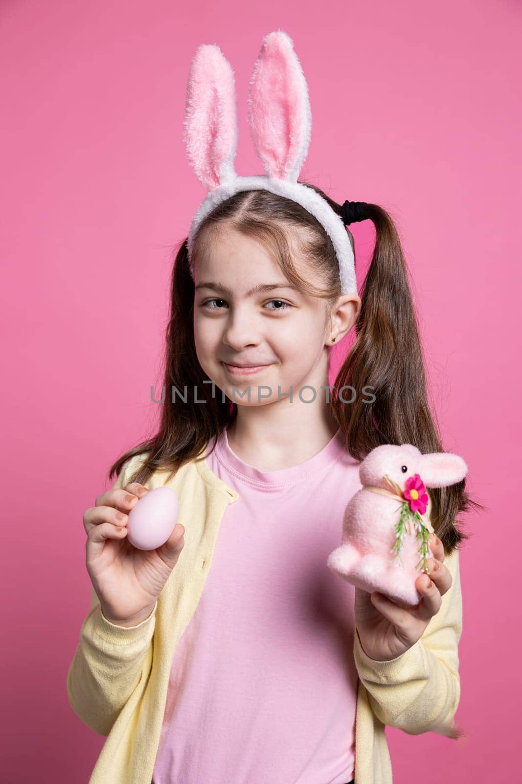 Lovely positive kid holding fluffy cute ornaments in front of camera by DCStudio