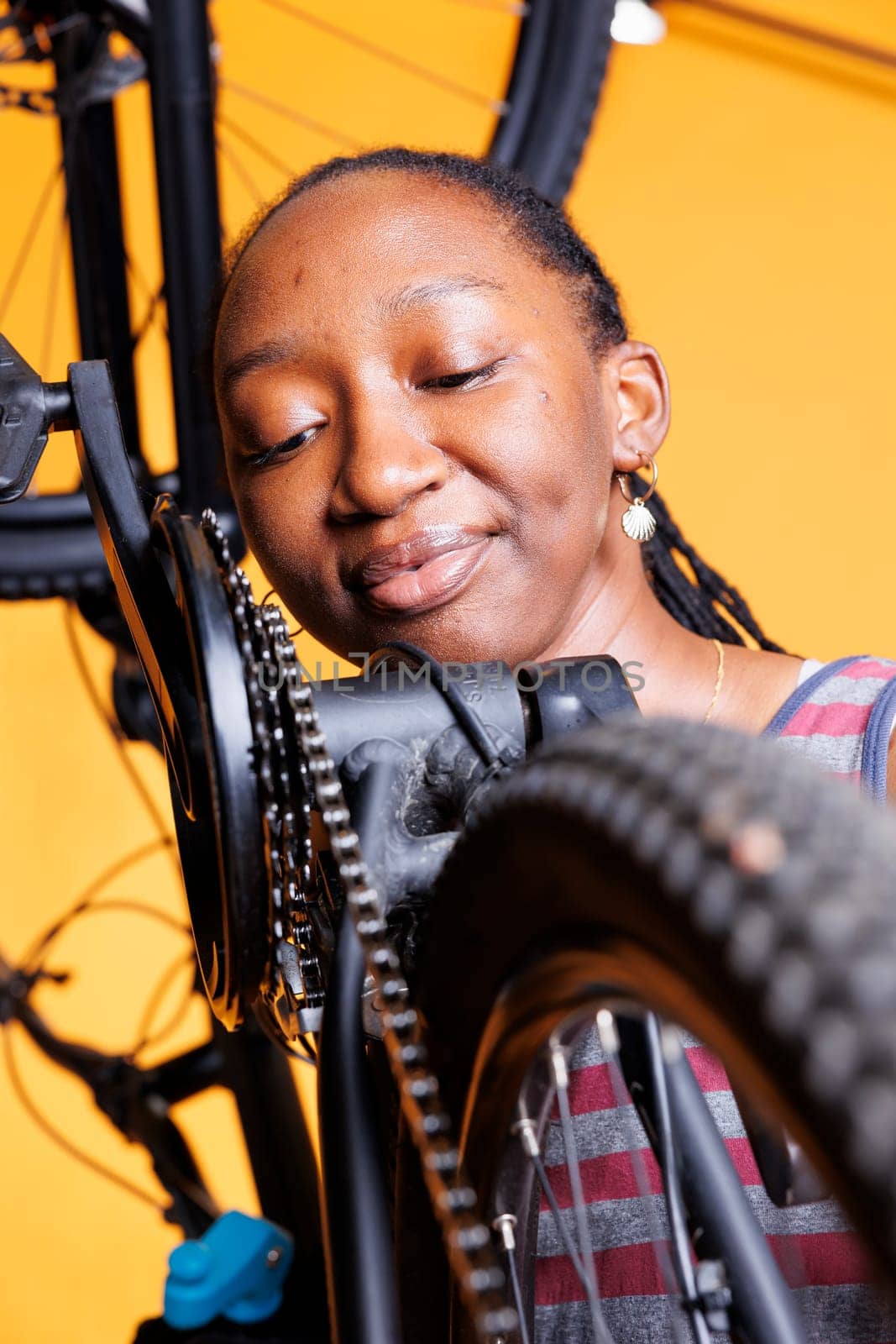 Young woman inspects bike components by DCStudio