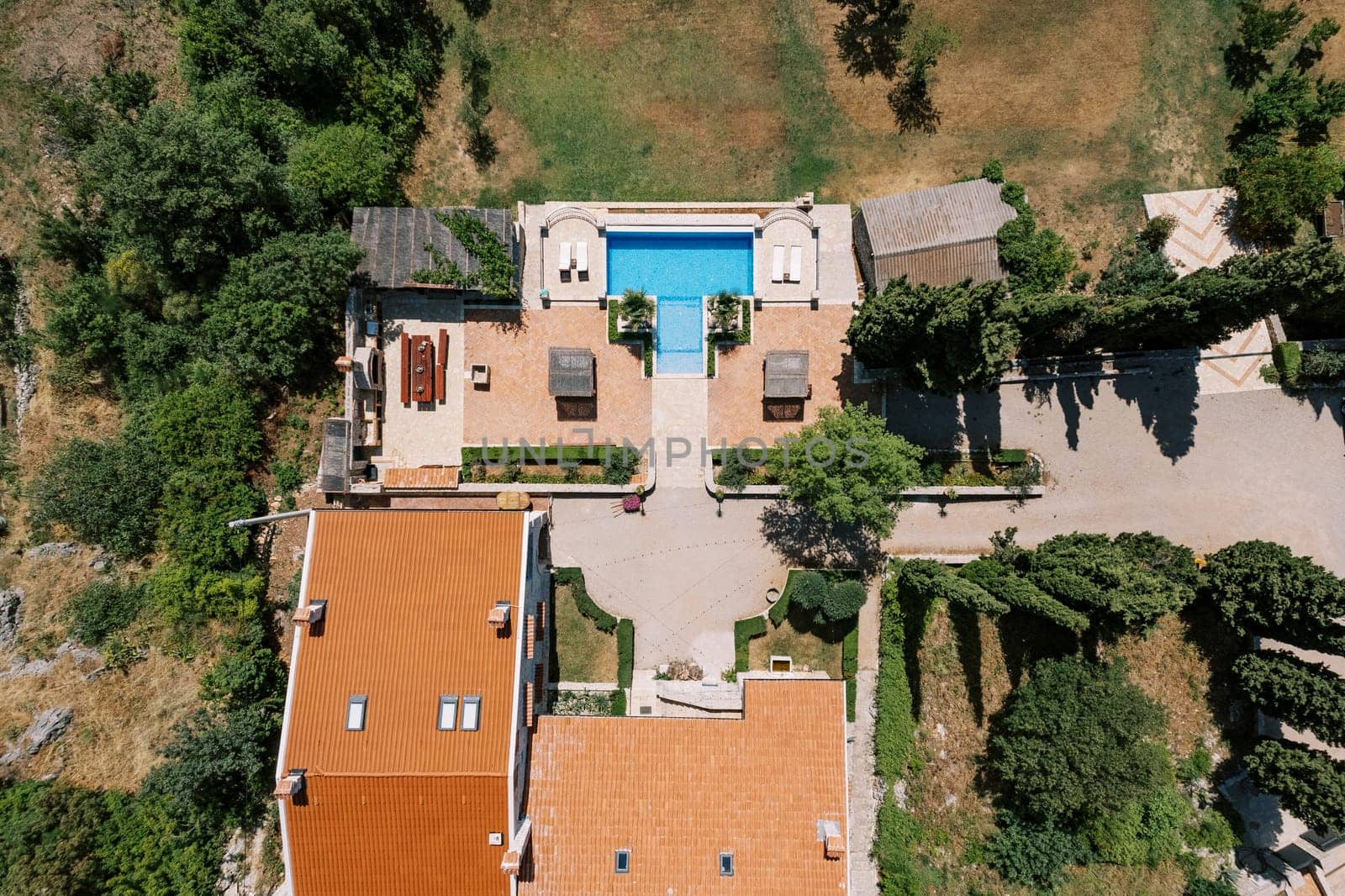 Ancient villa with a swimming pool in a green garden and sun loungers. Drone by Nadtochiy