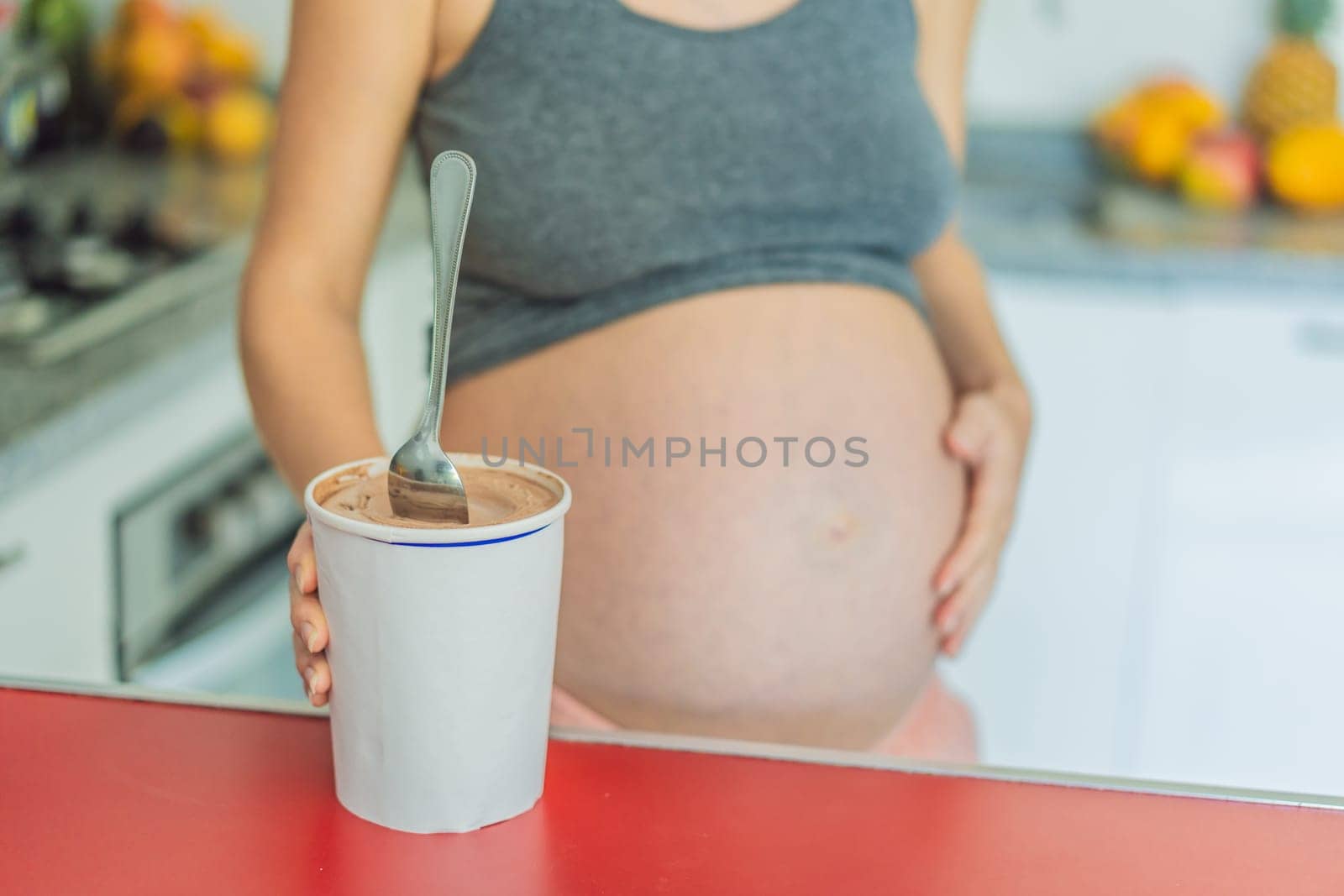 Happy pregnant young woman eating ice cream by galitskaya