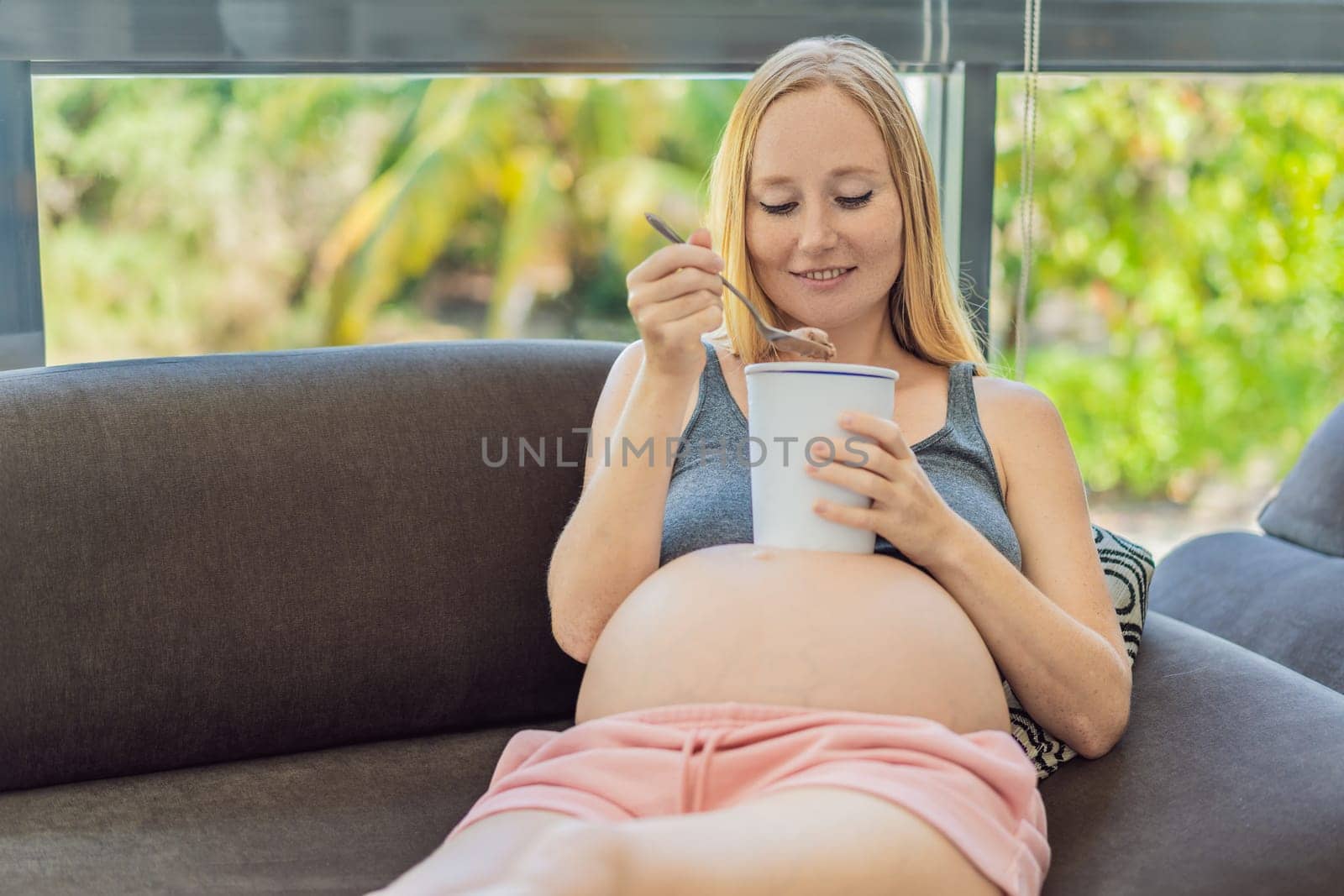 Happy pregnant young woman eating ice cream.