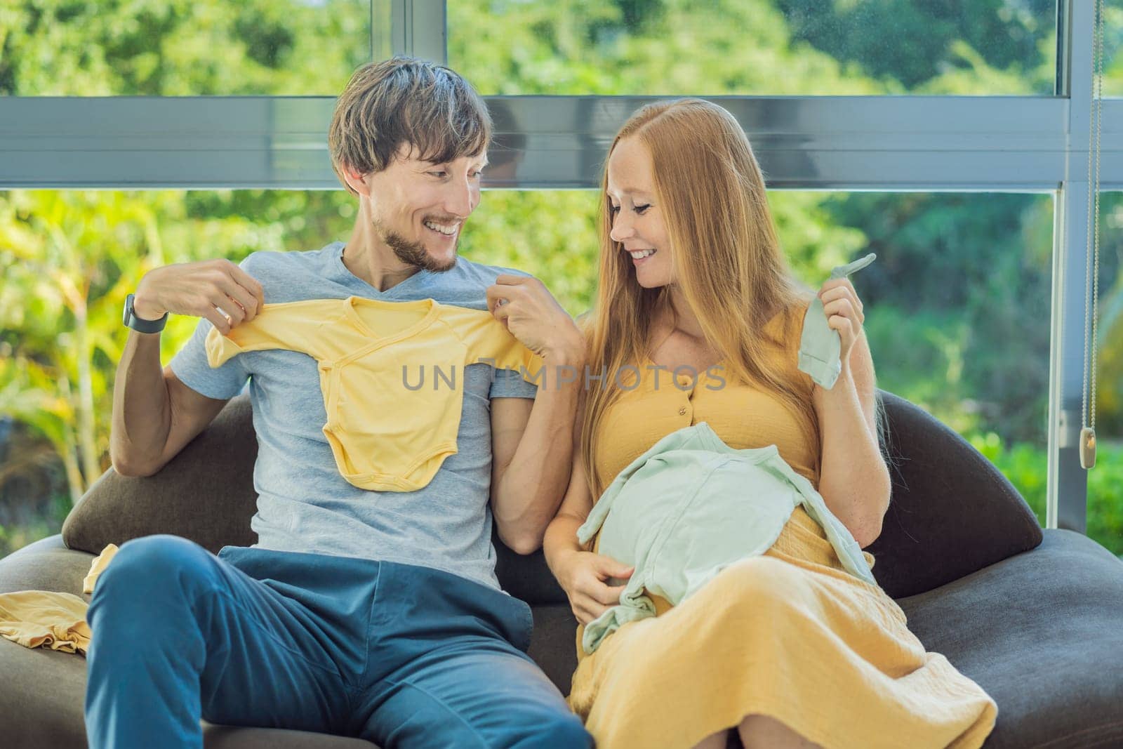 In a heartwarming scene, the future mom and dad hold their unborn baby's clothes in their hands, savoring the joy of anticipation and shared excitement for their little one's arrival by galitskaya