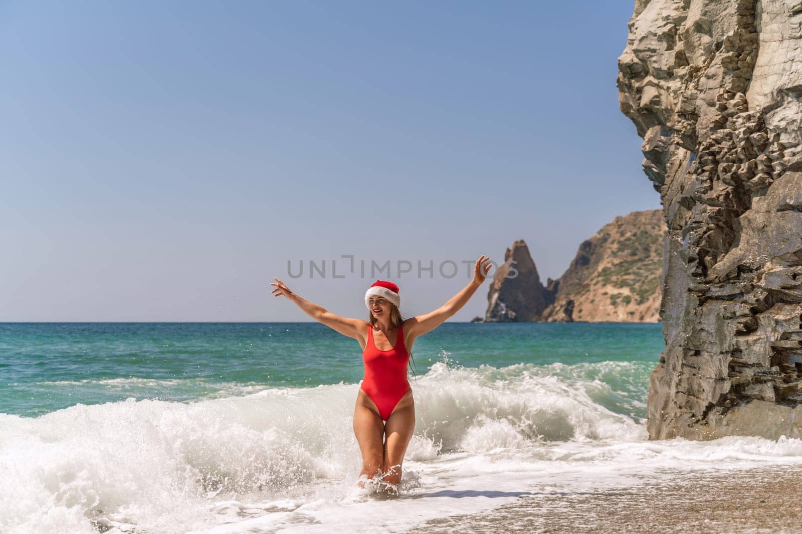 A woman in Santa hat on the seashore, dressed in a red swimsuit. New Year's celebration in a hot country. by Matiunina