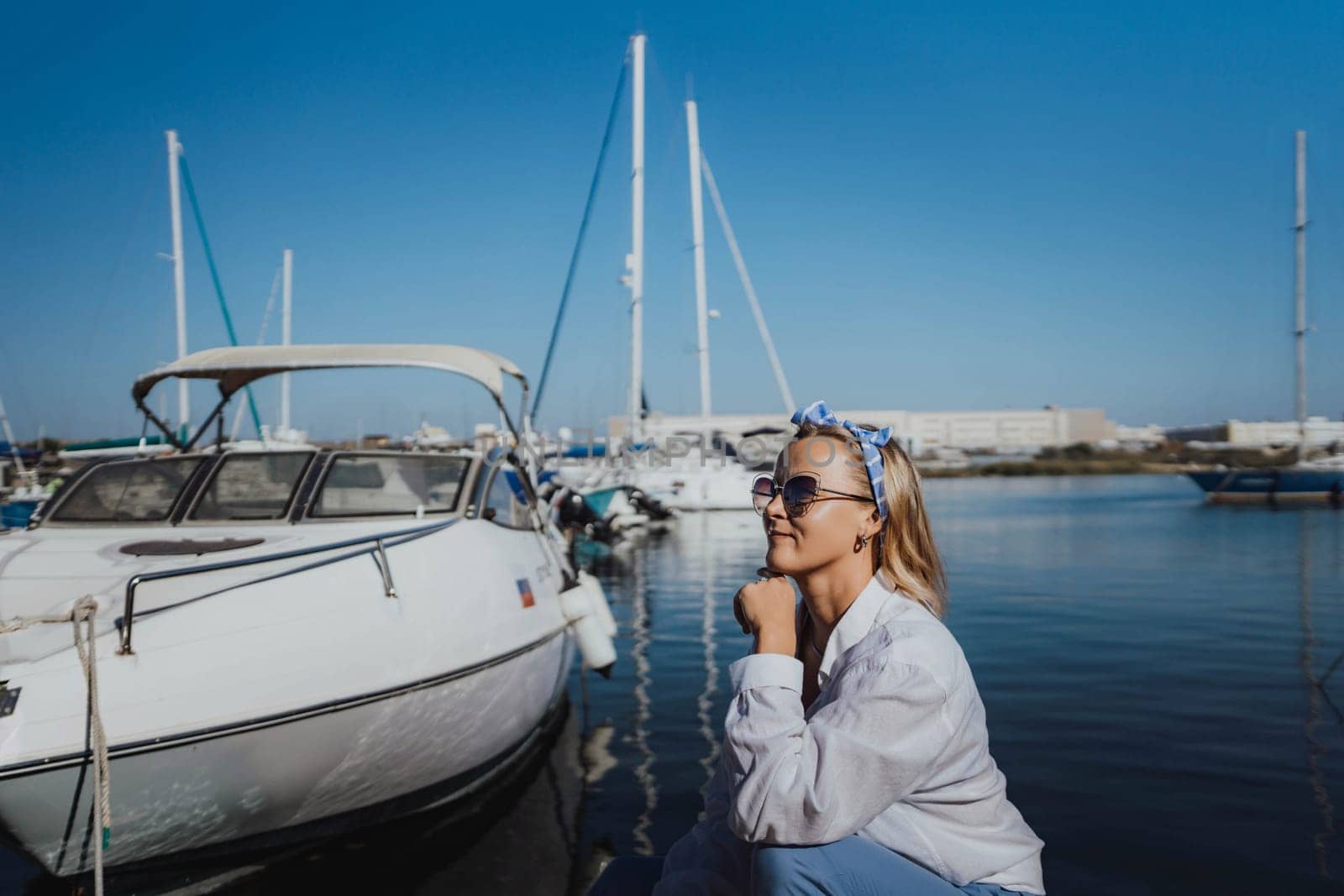 Woman in white shirt in marina , surrounded by several other boats. The marina is filled with boats of various sizes, creating a lively and picturesque atmosphere. by Matiunina