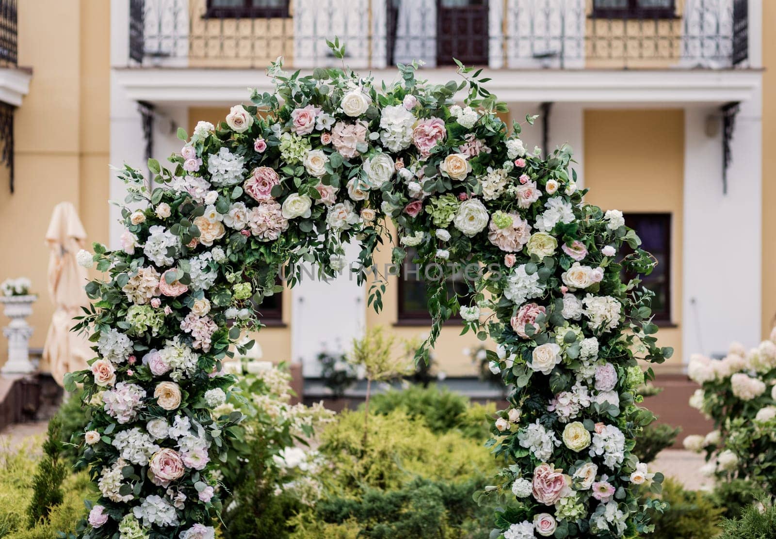 Circle wedding arch decorated with white flowers and greenery outdoors. Wedding setting. Floral composition