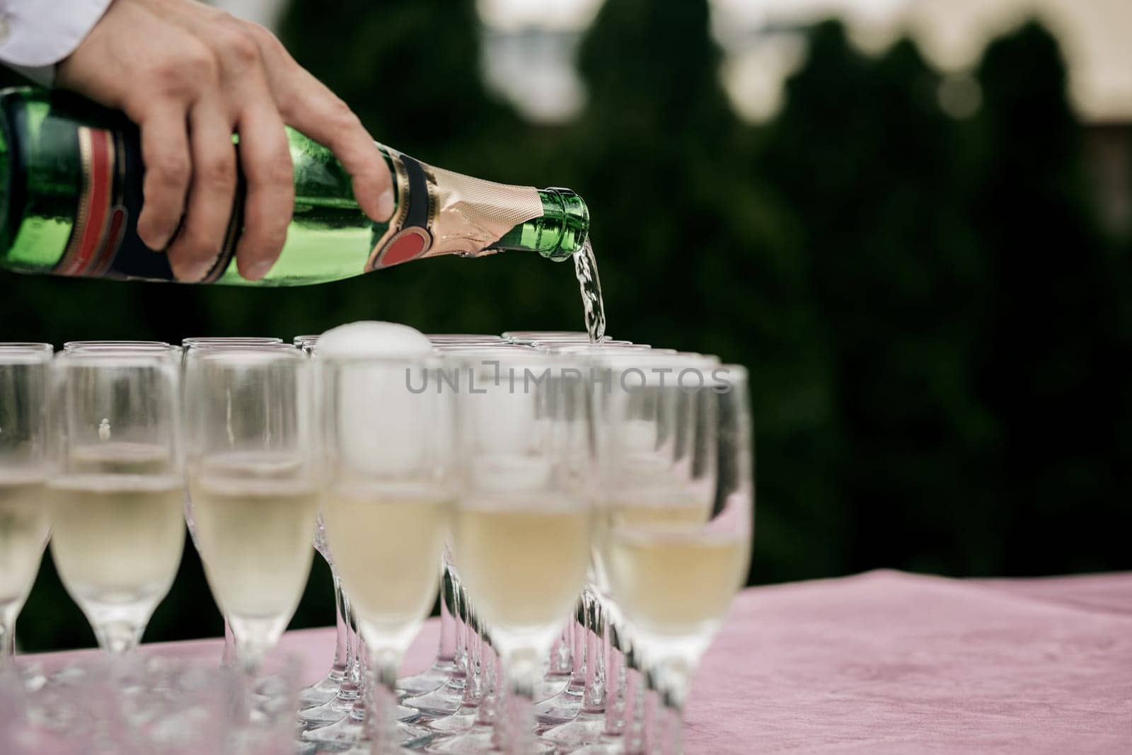 Man pours champagne in wineglasses. wedding