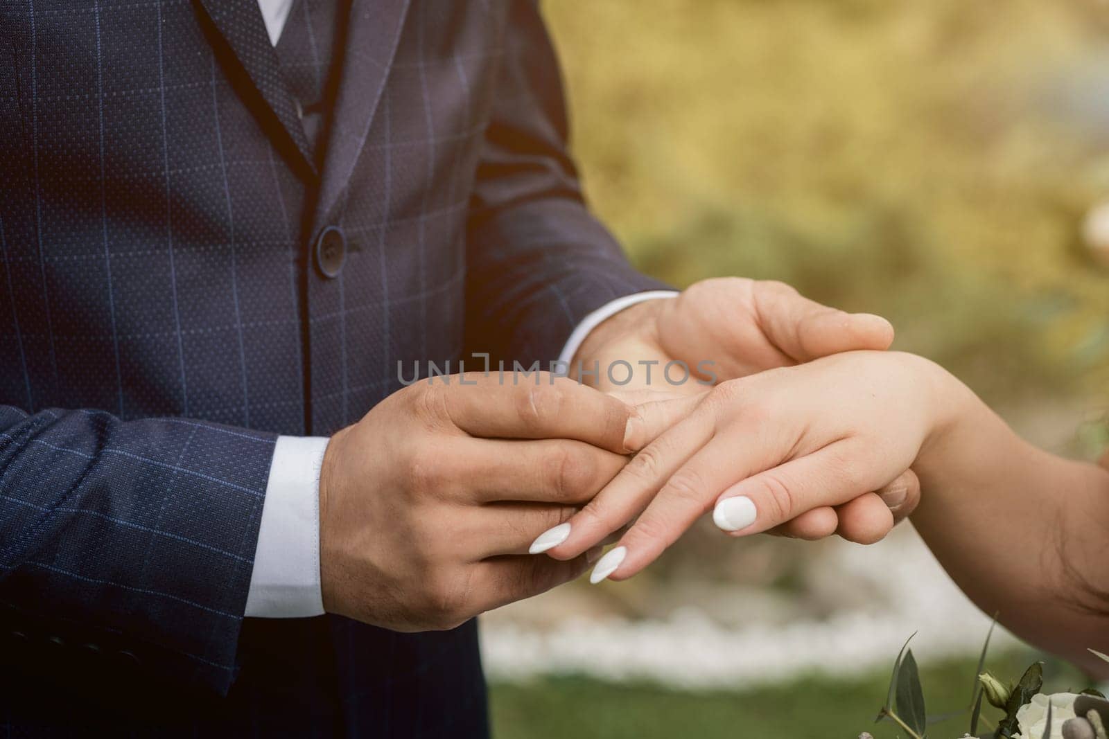 couple exchanging wedding rings during their wedding ceremony outdoors. Cropped shot of groom putting a wedding ring on the finger of the bride.