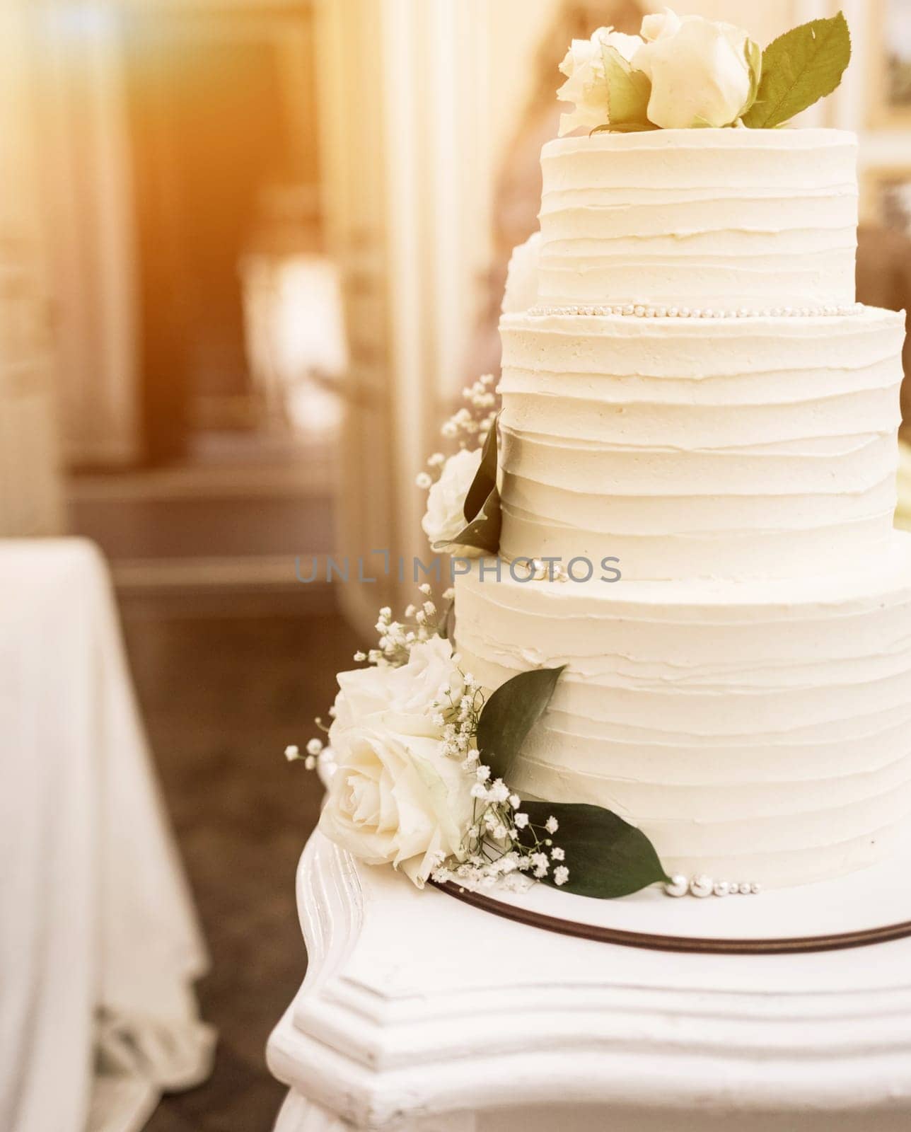 Three-tiered white wedding cake decorated with flowers