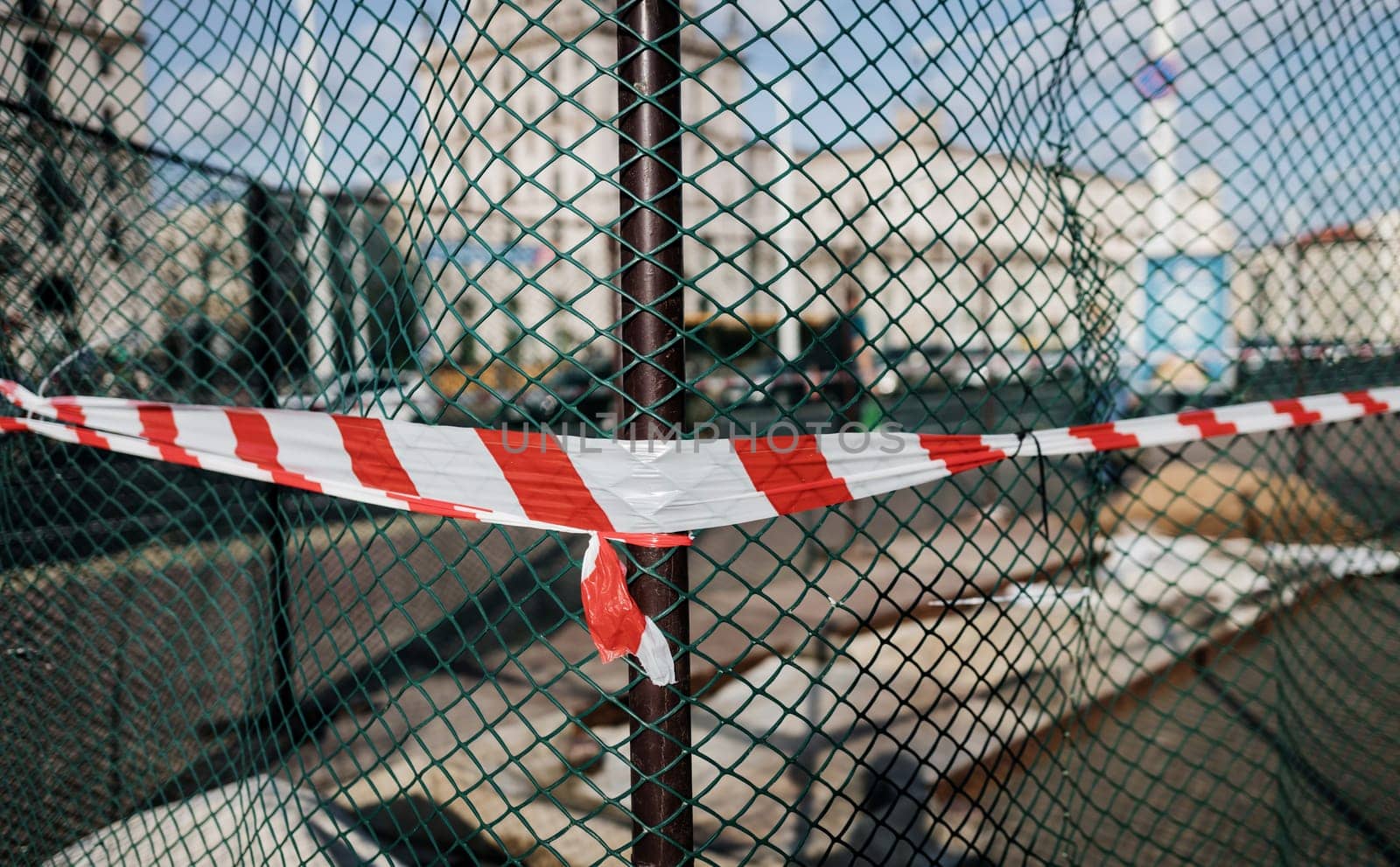 Signal protective tape on grid. The fence on the construction site is made of signal tape. Red and white ribbon close-up.