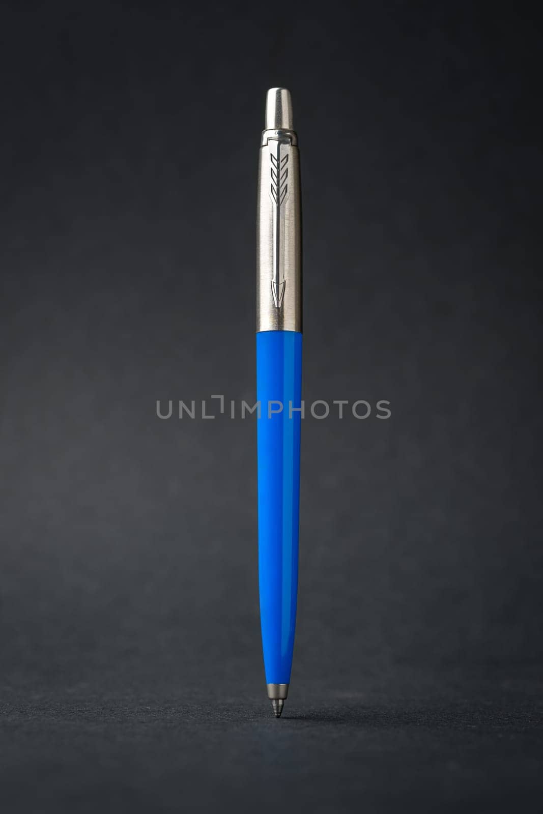 Blue plastic and metal ballpoint pen on dark gray background by Sonat