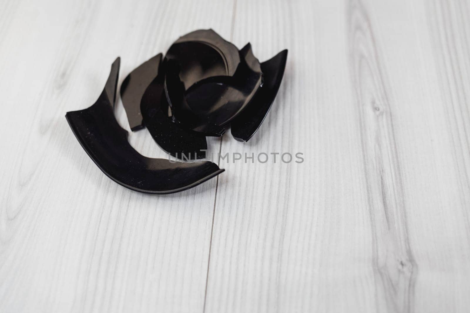 Black shards of a broken plate on gray background. splinters of a shattered dish. Fragments of a white plate on the floor. 