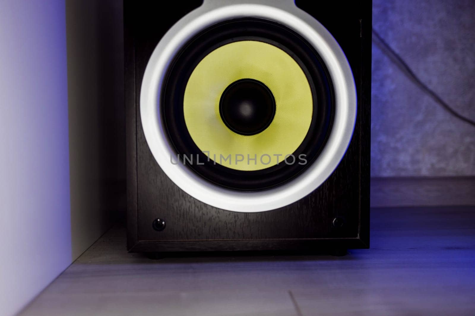 Music studio speaker, with a yellow membrane, on floor