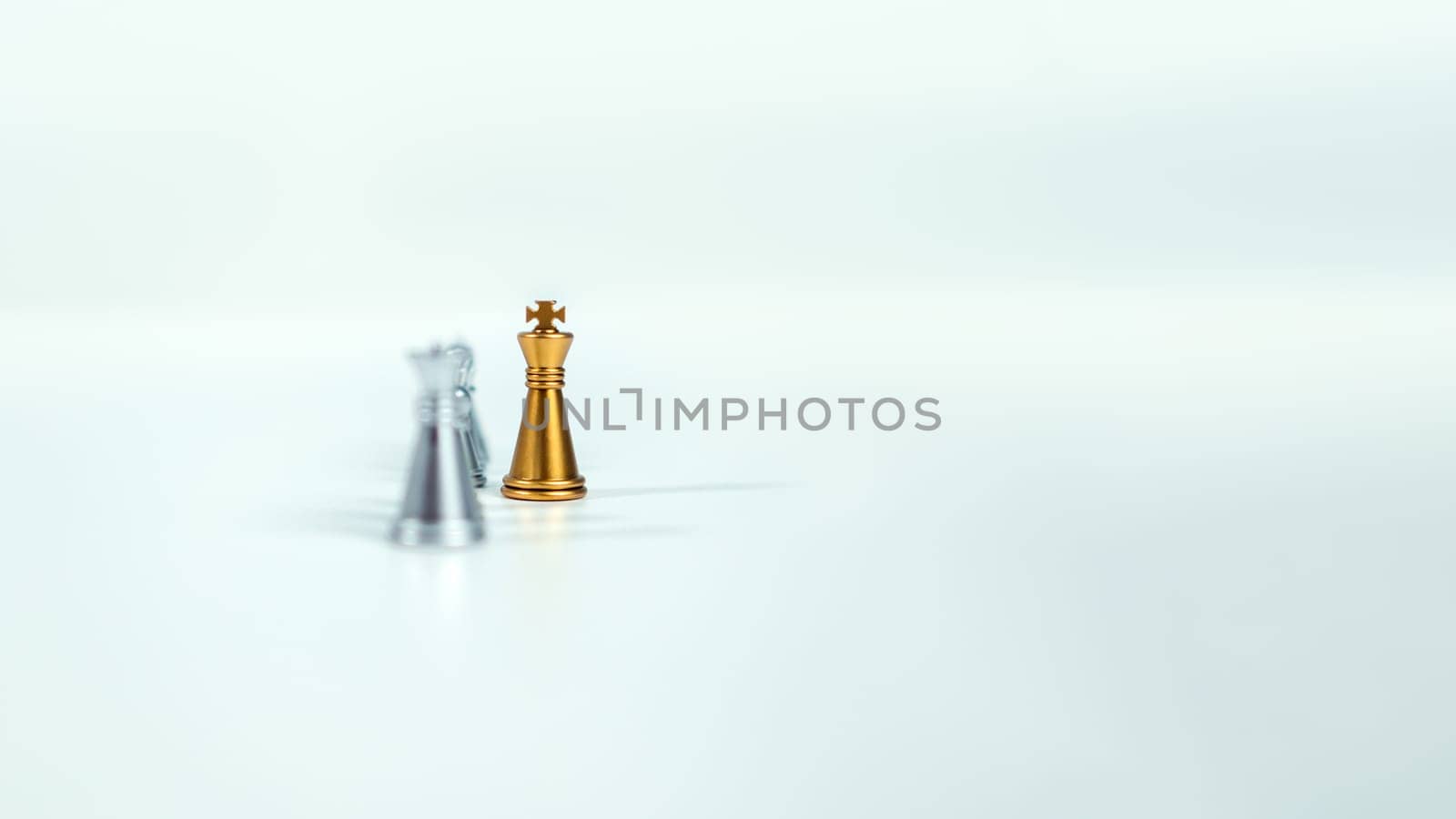 Golden king chess on the board in front of silver chess pieces on white background with copy space, Leadership, fighter, business leadership, competition, confrontation, and business strategy concept.