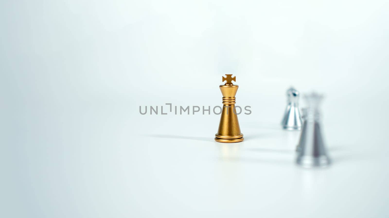 Golden king chess on the board in front of silver chess pieces on white background with copy space, Leadership, fighter, business leadership, competition, confrontation, and business strategy concept.