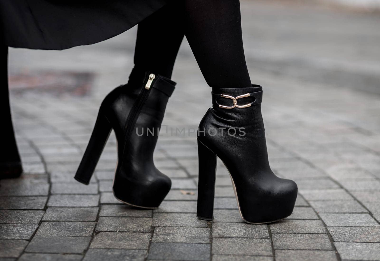 Elegant outfit. Closeup of stylish black ankle boots. Fashionable girl on the street. City lifestyle. Female fashion