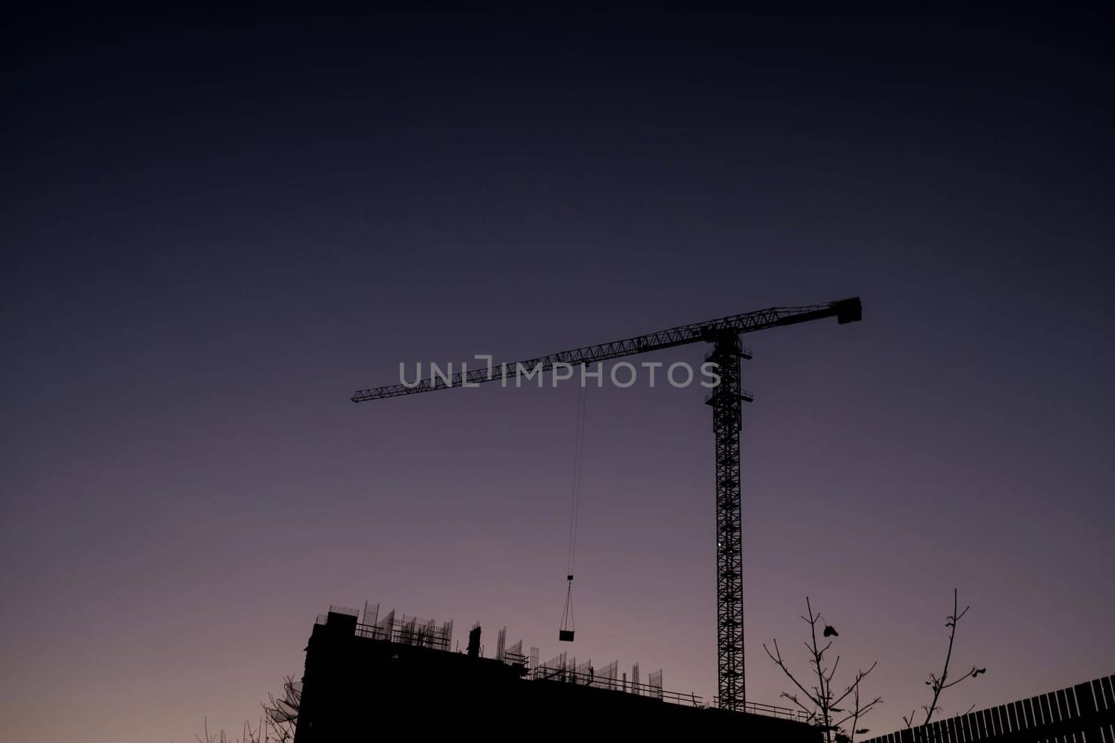 New construction site with crane and mechanical equipments on sunset