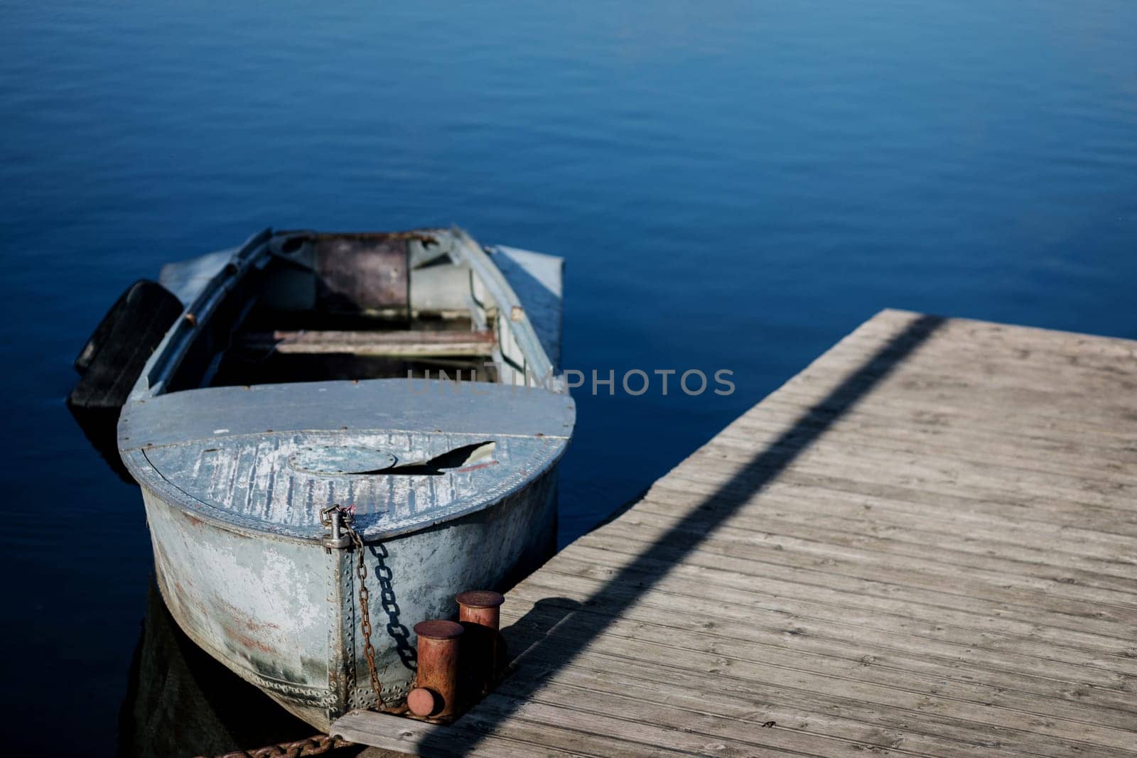 Old small boat floating on the lake near the pier.